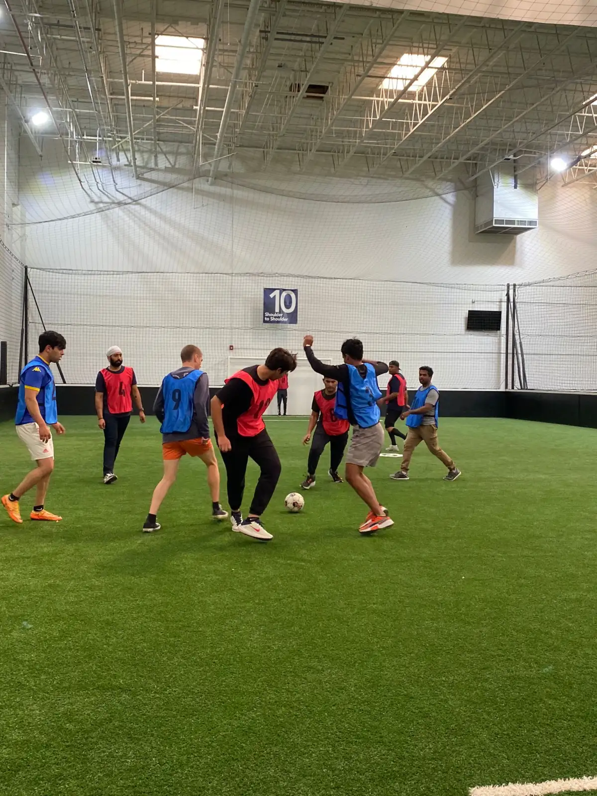 Students playing five-a-side football on an indoor turf pitch